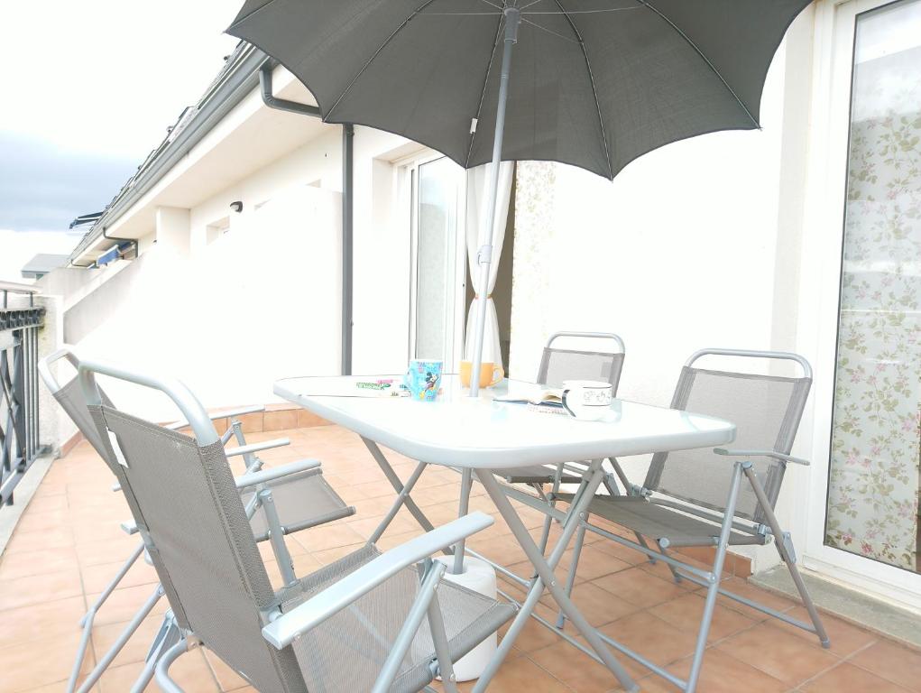 - une table et des chaises avec un parasol dans la chambre dans l'établissement Mi piso en la ría, à Barreiros