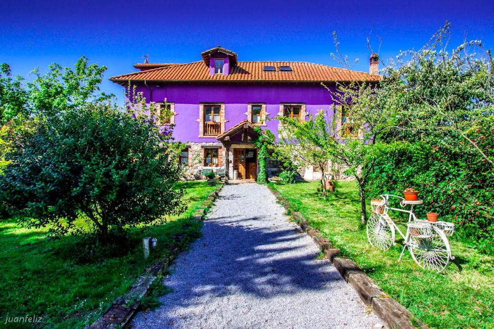 uma casa roxa com uma estrada de cascalho em frente em El Búho de la Remolina em Bode