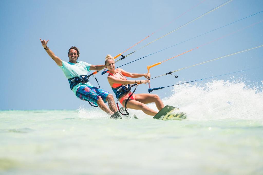 a man and woman water skiing in the ocean at Zanzibar White Sand Luxury Villas & Spa - Relais & Chateaux in Paje
