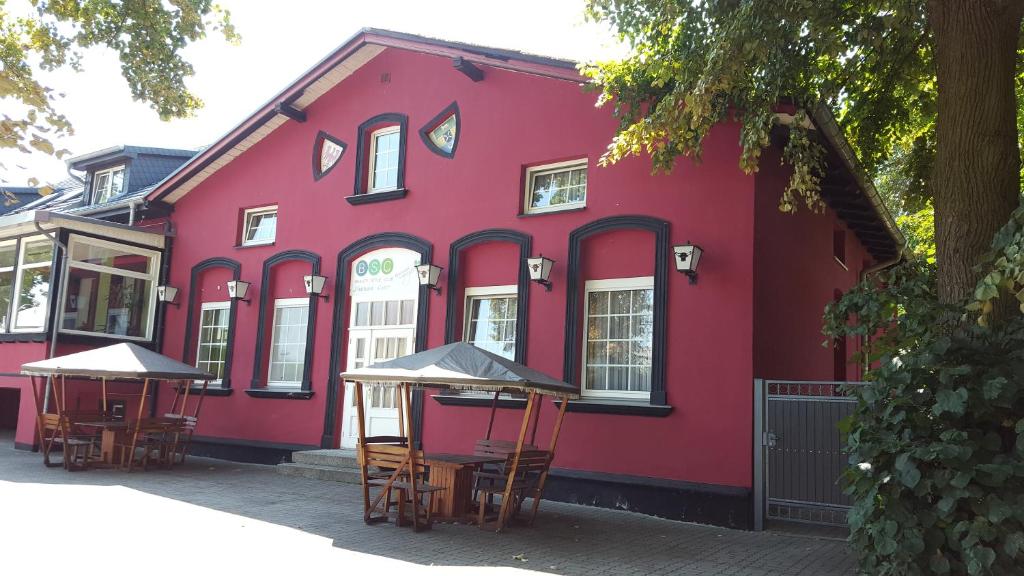 a red building with tables in front of it at Pension Am Mellensee in Saalow