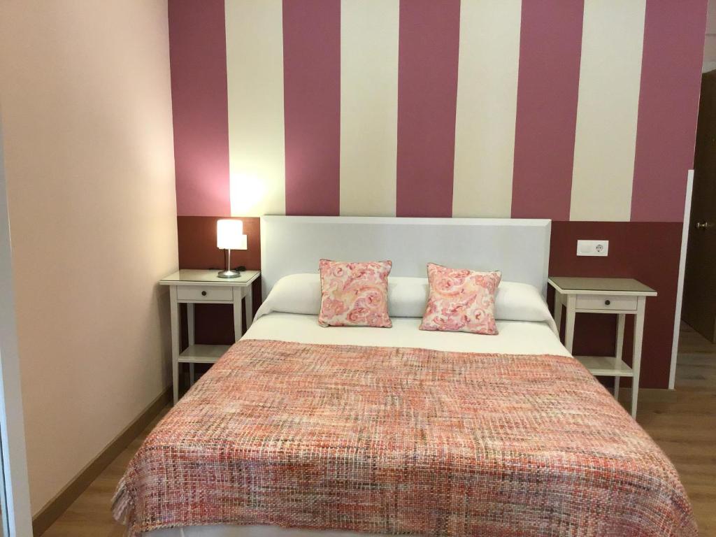 um quarto com uma cama com duas mesas e duas almofadas em Apartamento Ribadesella em Ribadesella