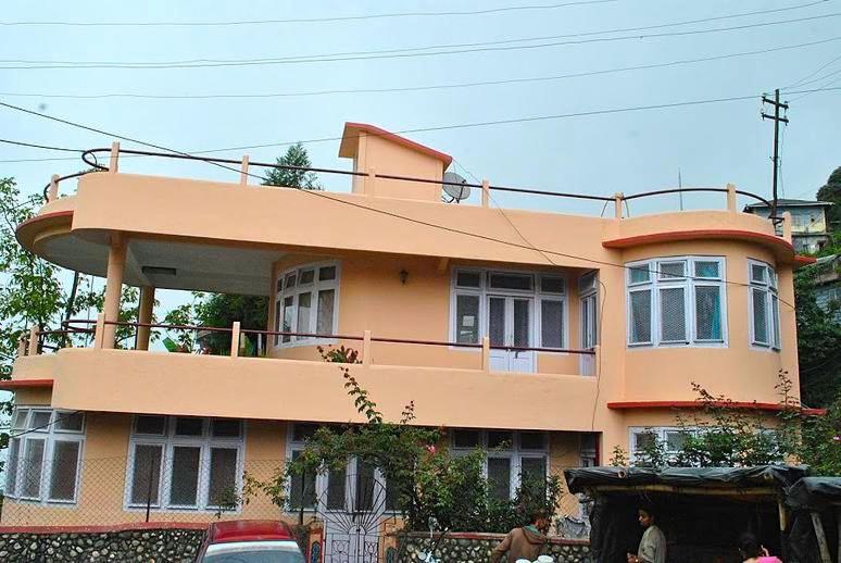 uma grande casa laranja com pessoas à frente dela em Misty Views- Susama Villa em Darjeeling