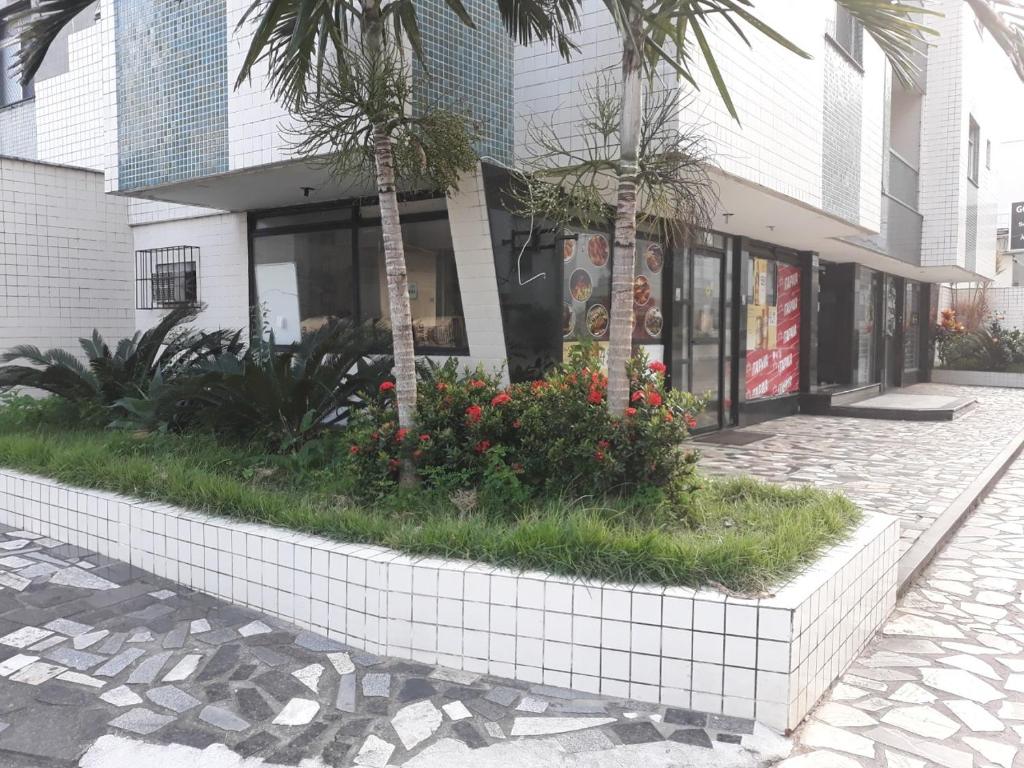 un edificio con palmeras y flores delante de él en Apartamento Guarapari, en Guarapari