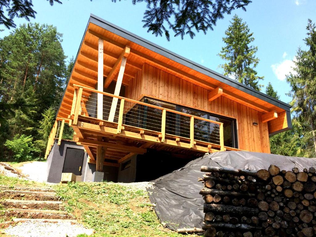 a log cabin with a deck and a pile of logs at Chalet Slovensky Raj in Smižany