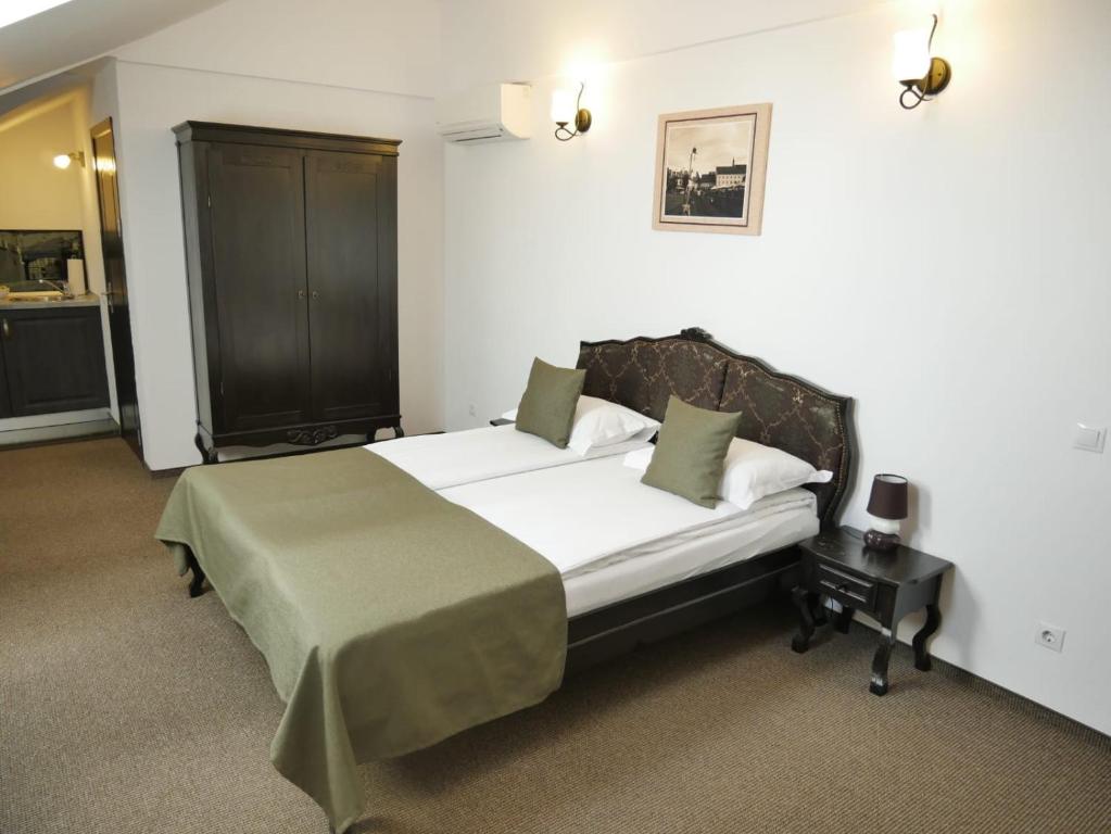una camera da letto con un grande letto con lenzuola bianche e cuscini verdi di Sibiu City Center Apartments a Sibiu