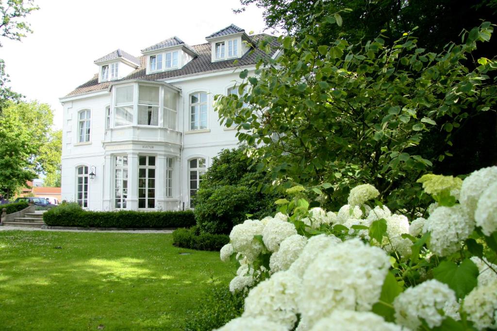 een groot wit huis met bloemen in de tuin bij Hotel Hochzeitshaus in Aurich