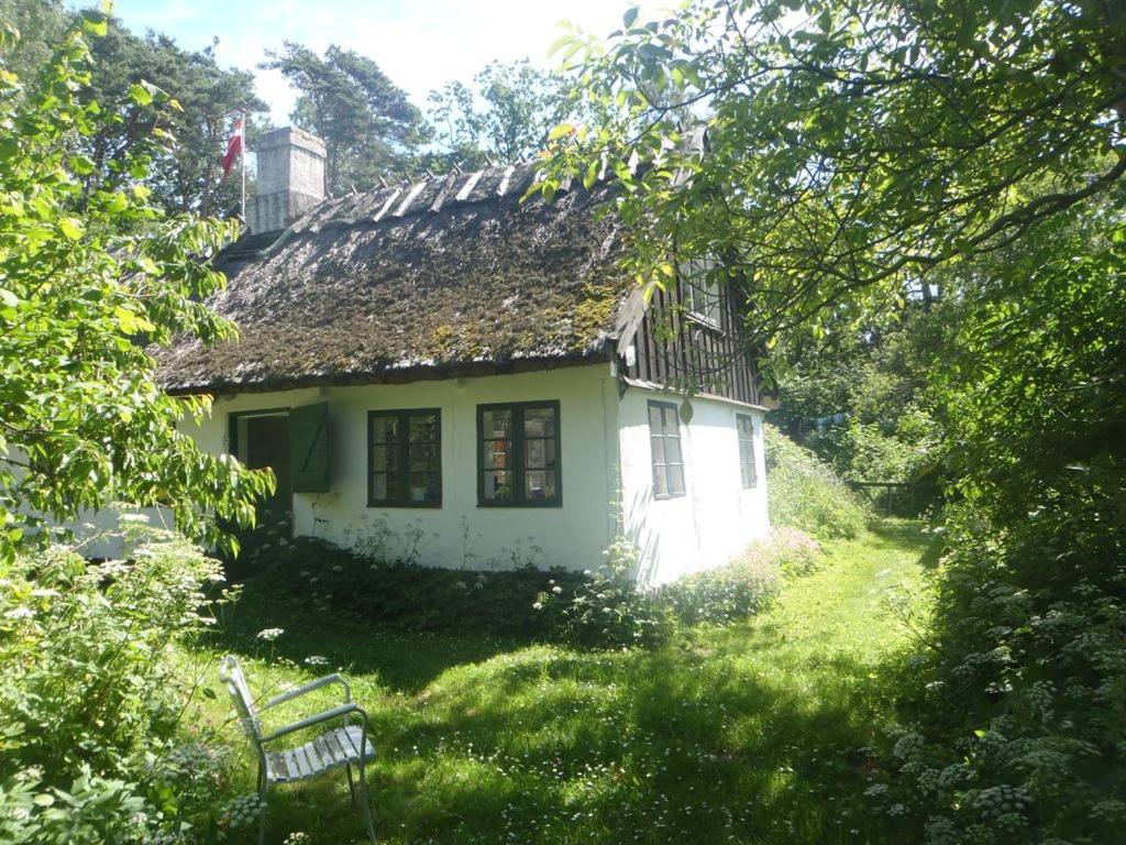 uma pequena casa branca com telhado de palha em GOGGE's HUS em Tisvildeleje