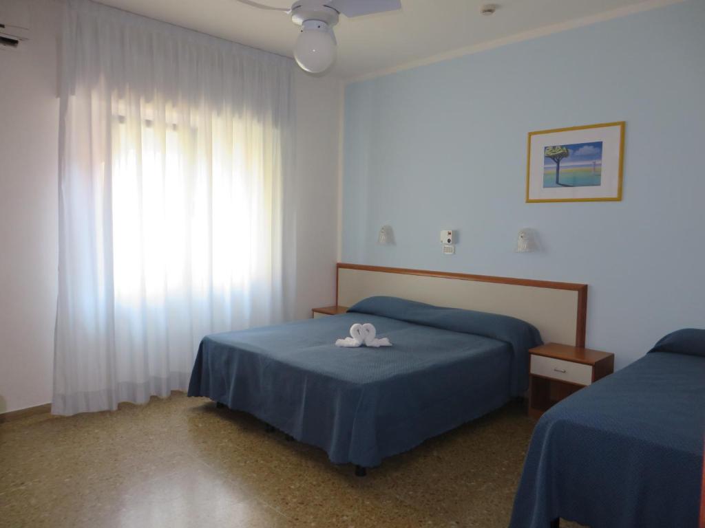 a bedroom with two beds and a window at Hotel Maxim in Caorle