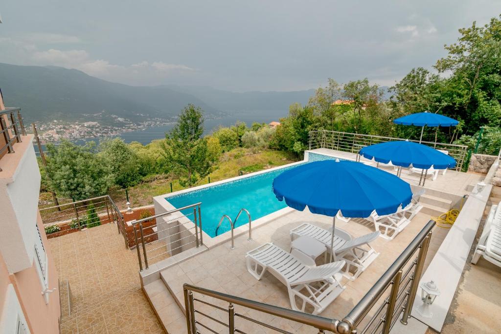 a swimming pool with chairs and umbrellas and a pool at Apartments Mitrovic in Lustica