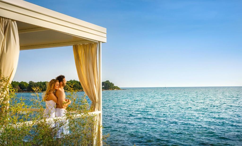 a bride and groom standing under a tent by the water at Amber Sea Luxury Village Mobile Homes in Novigrad Istria