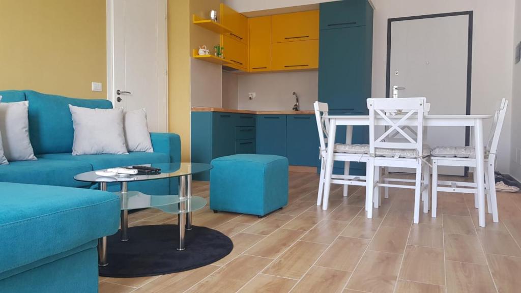 a living room with a blue couch and a table and chairs at Shengjin - Helios Home in Shëngjin