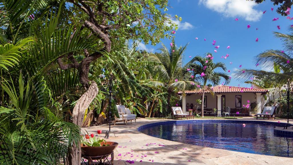 a swimming pool with palm trees and a house at Casa de São José Hotel Boutique in Camocim