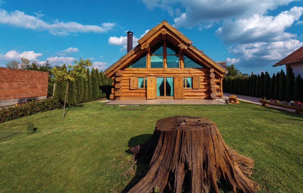 a log cabin with a tree stump in front of it at Baranjska eko drvena kuća in Kopačevo