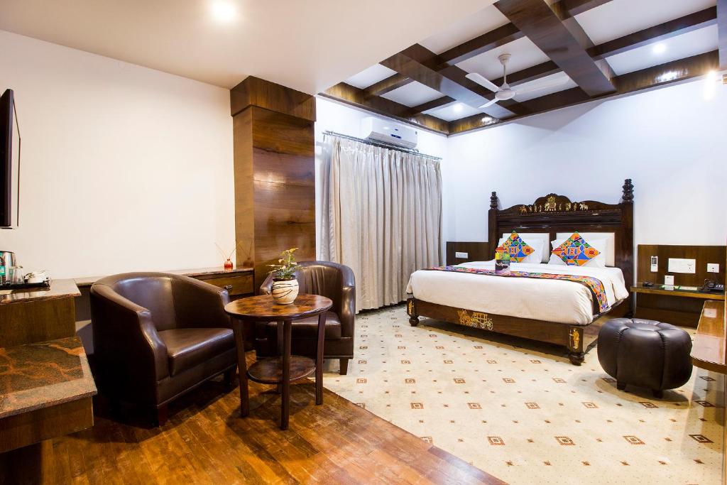 a bedroom with a bed and a desk and a chair at Hotel Lok Sagar Mysore in Mysore