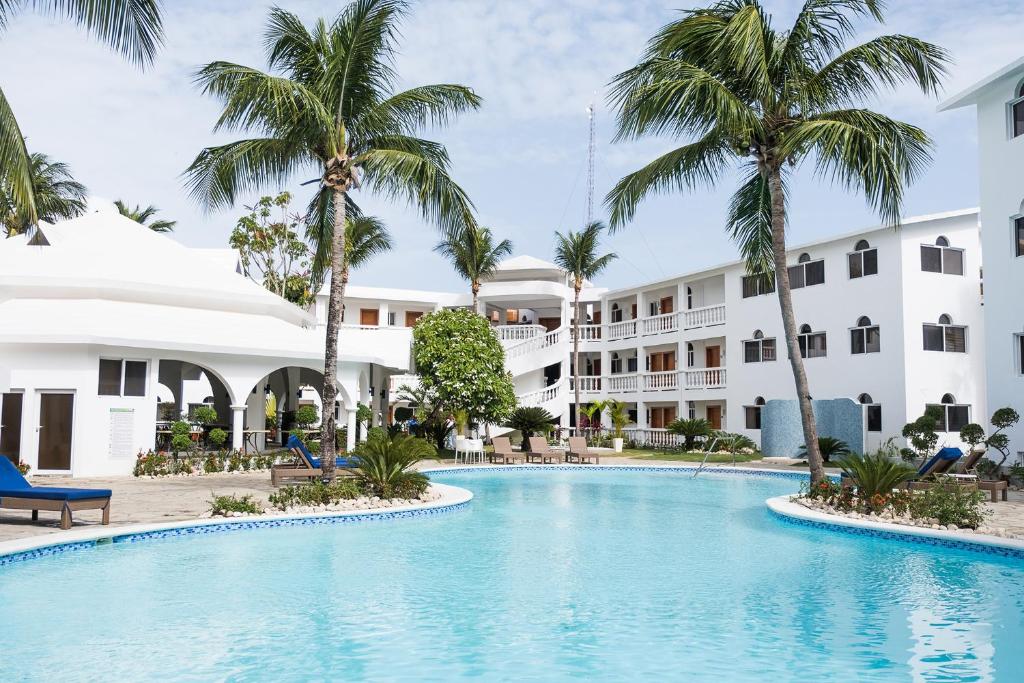 uma piscina com palmeiras em frente a um edifício em Ocean Palms Residences em Cabarete