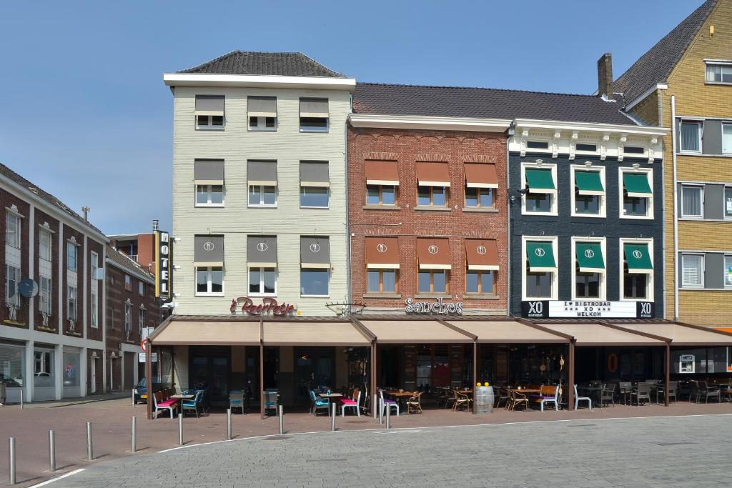 een groep gebouwen op een straat met tafels en stoelen bij Hotel Roermond Next Door in Roermond