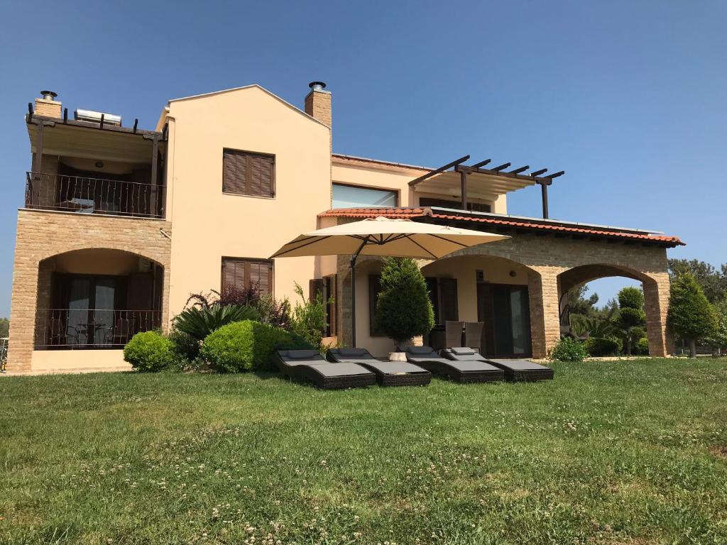 a house with an umbrella in front of a yard at M Varkes Villa in Nea Moudania
