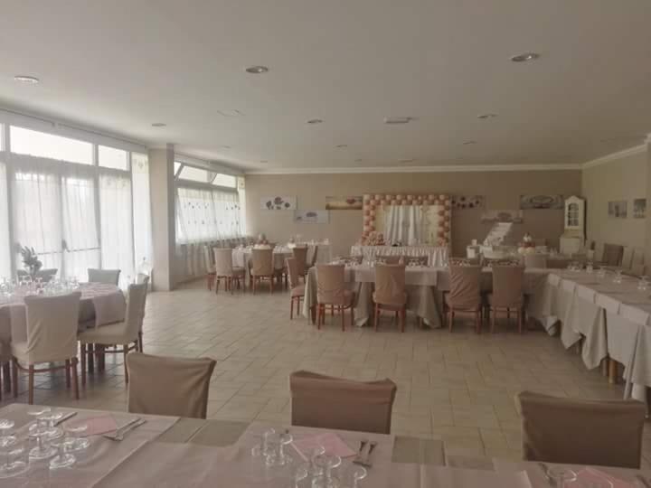 un salón de banquetes con mesas y sillas blancas en Agriturismo "Lo zafferano", en Aprilia
