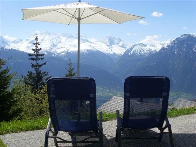 two chairs sitting under an umbrella with a view of mountains at Wallisblick in Blatten bei Naters