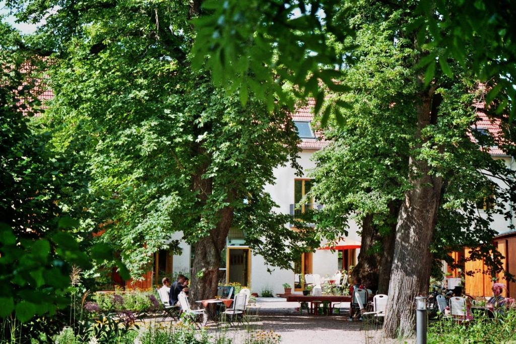 a white building with tables and chairs and trees at Bio Hotel Kipperquelle in Weimar