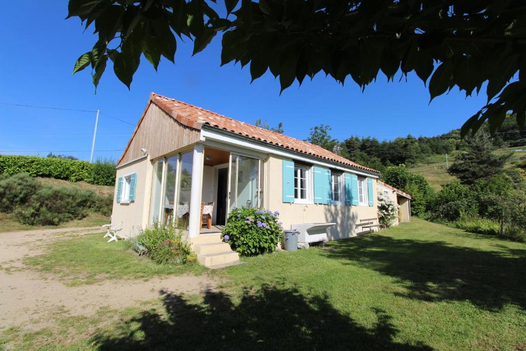 Casa blanca pequeña con ventanas azules y patio en Gite de la Vialle en Lamastre
