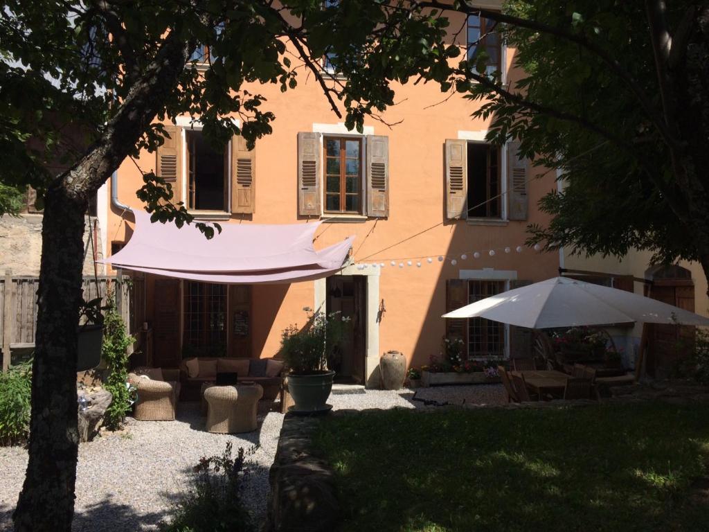 une maison avec un parasol dans la cour dans l'établissement Le Val d'Ailleurs, à Jausiers