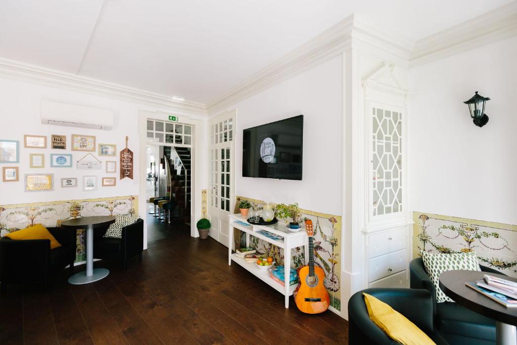 - un salon aux murs blancs avec une table et des chaises dans l'établissement Lisbon South Hostel, à Almada