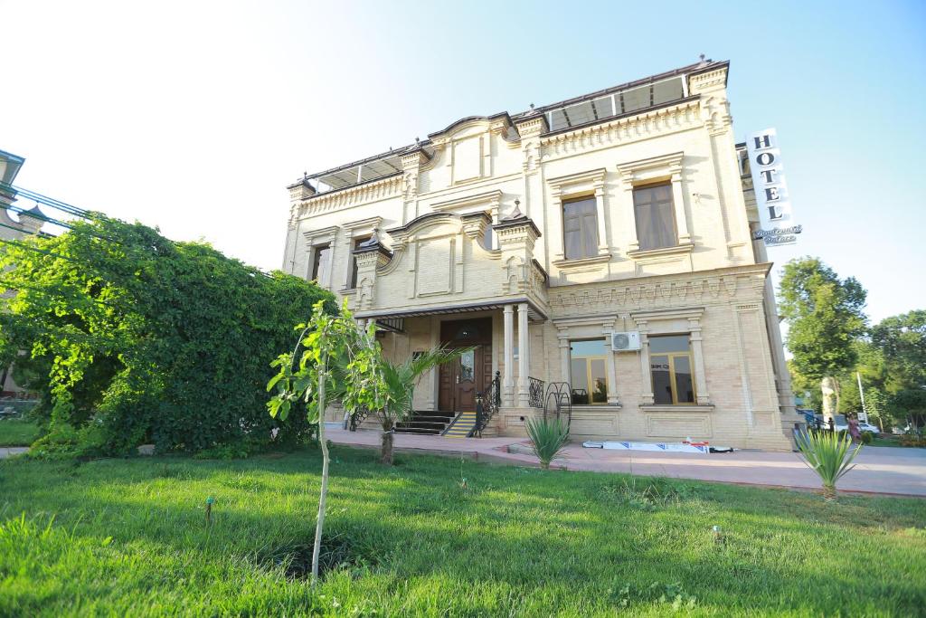 een groot wit gebouw aan de kant van een straat bij Boulevard Palace Hotel in Samarkand