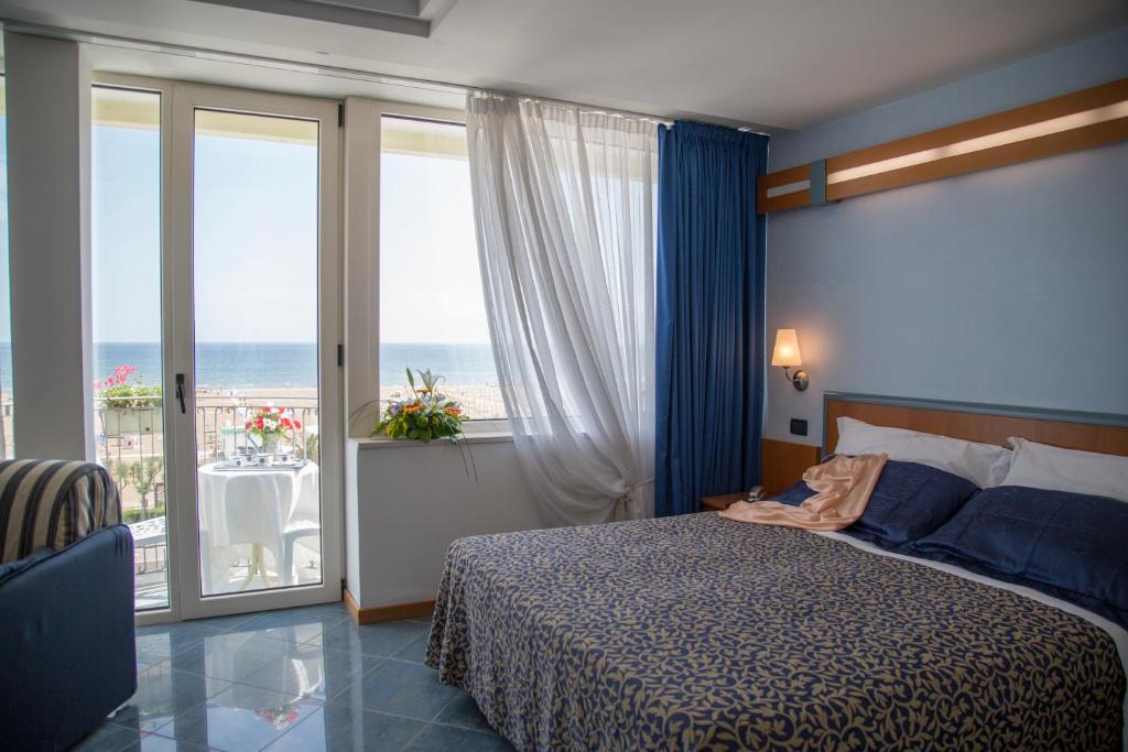 een slaapkamer met een bed en uitzicht op de oceaan bij Hotel Ancora in Rimini