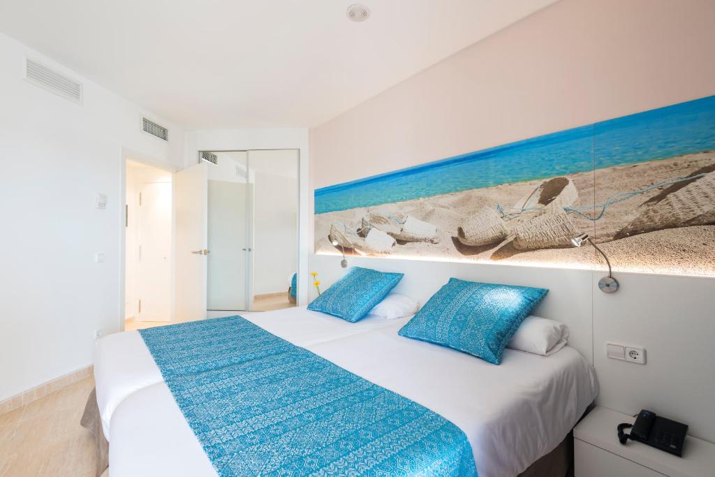 a bed room with a blue bedspread and a blue wall at Aparthotel Tropic Garden in Santa Eularia des Riu