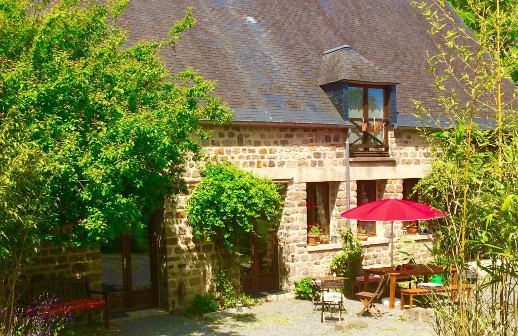 a brick house with a red umbrella in front of it at Normandy Inn in Montbray