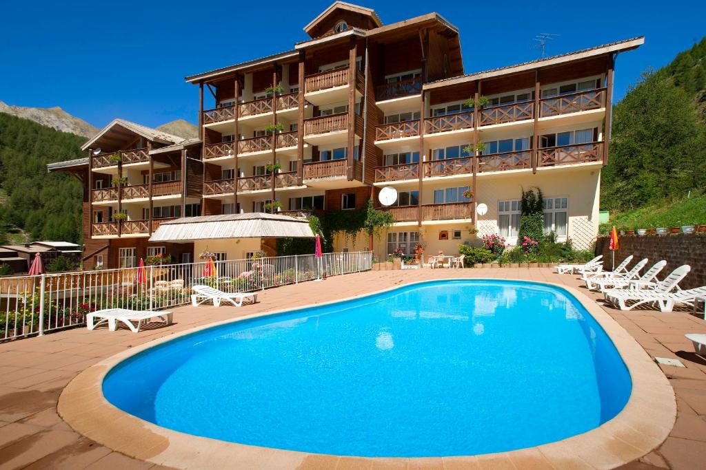 a hotel with a large swimming pool in front of a building at Hôtel du Hameau in La Foux