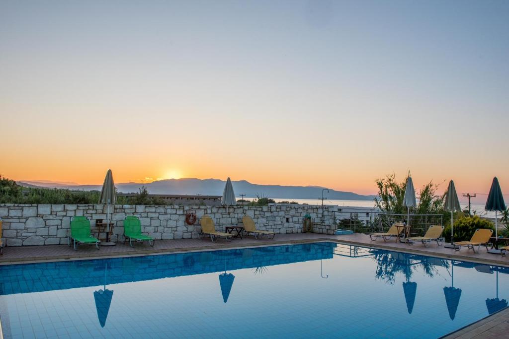 a swimming pool with a sunset in the background at Christiana Apartments in Gerani Chanion