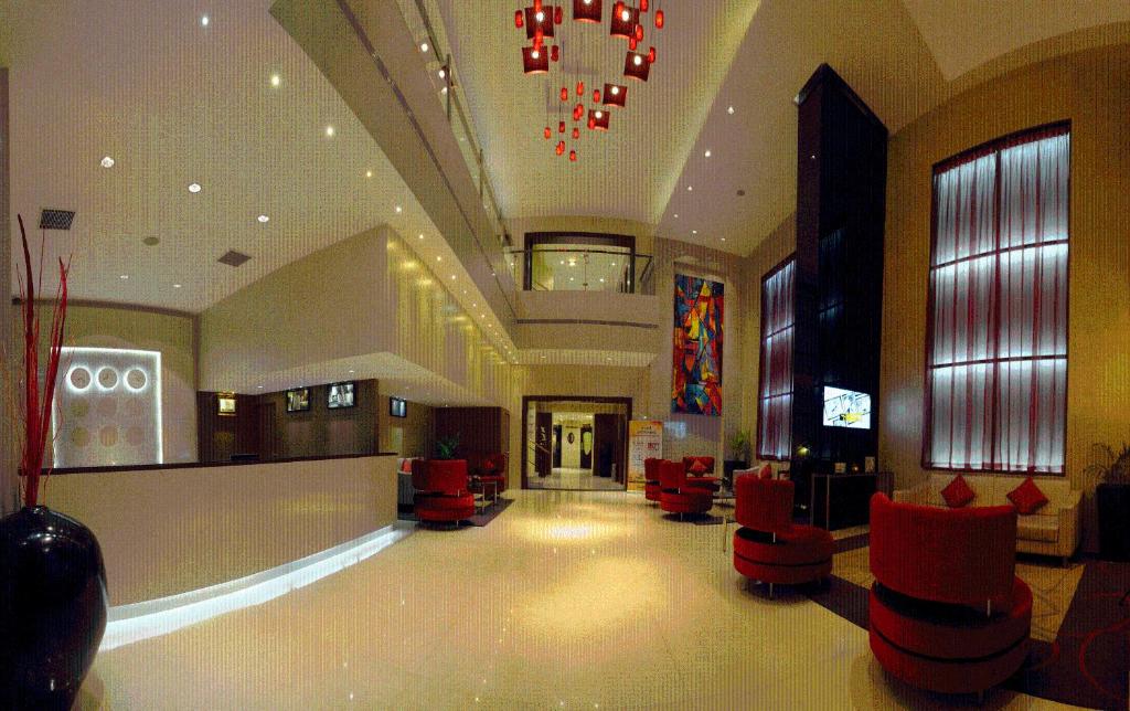 un vestíbulo con una sala de espera con sillas rojas en CAG Pride en Coimbatore