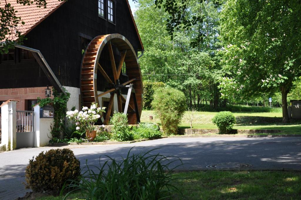 eine Scheune mit einem Wasserrad neben einem Haus in der Unterkunft Landgasthof Geiersmühle in Vielbrunn