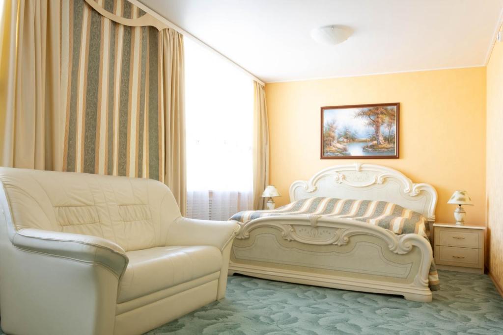 a white bed and a couch in a room at Leningrad Hotel in Cherepovets