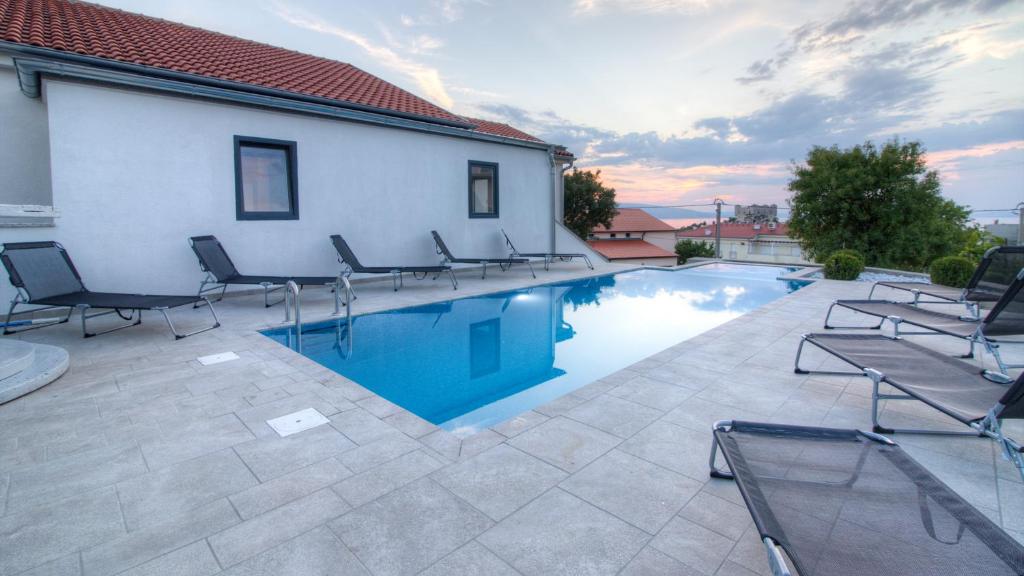 a swimming pool with lounge chairs next to a building at BC Eleven in Senj