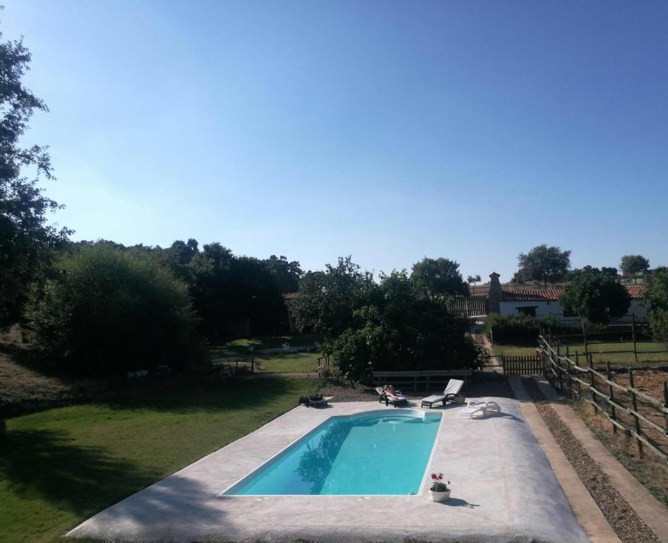 una piscina en un patio con gente sentada a su alrededor en Apartamentos Rurales Escobar & Jerez, en Valencia de Alcántara