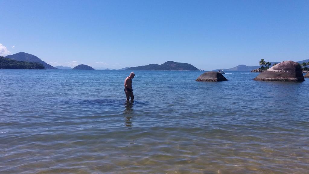 un hombre parado en un cuerpo de agua en Tranquilidade e diversão, en Mangaratiba