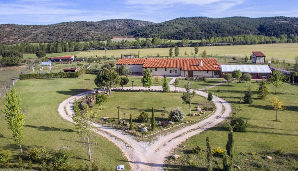 une vue aérienne sur une ferme avec une route en gravier dans l'établissement Hotel Rural Bioclimático Sabinares del Arlanza, à Puentedura