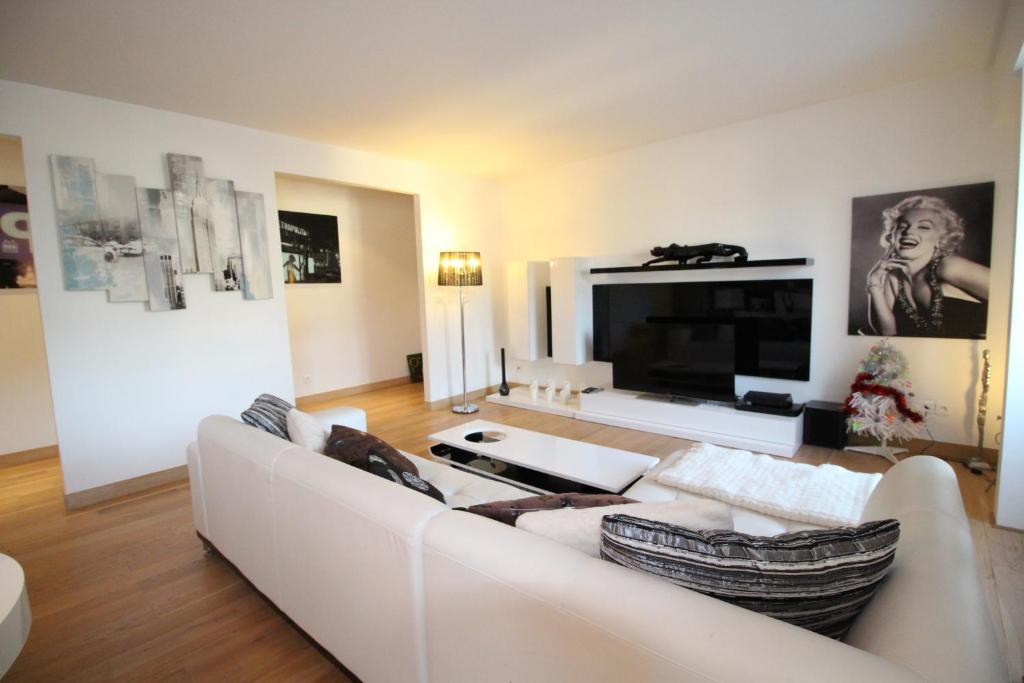 a living room with a white couch and a large tv at Appartements à Deauville dans Triangle d'Or in Deauville