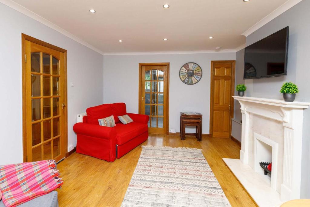 a living room with a red chair and a fireplace at Lomond Serviced Apartments- Inglewood in Alloa