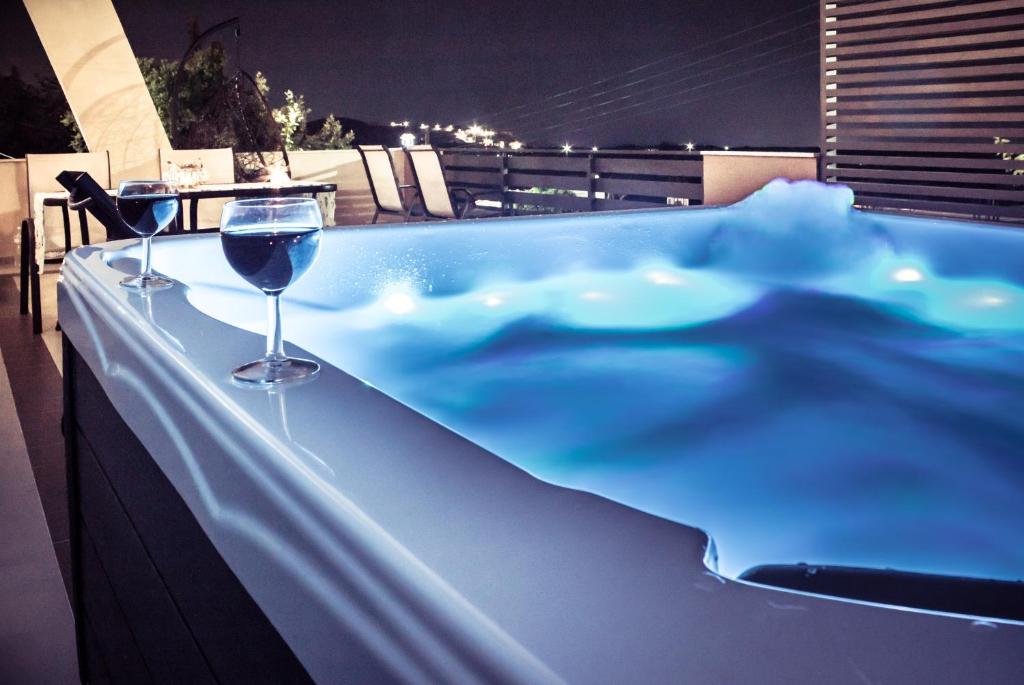 una vasca idromassaggio con un bicchiere di vino sul balcone di Andromache Villas a Roumelí