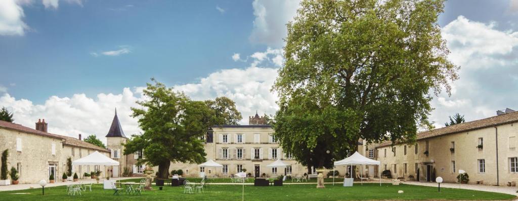 a building with tables and white umbrellas in front of it at Domaine du Griffier in Granzay