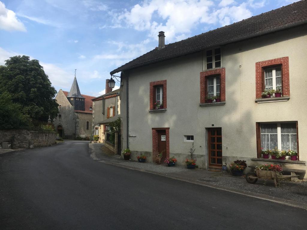 een wit huis met rode luiken op een straat bij La petite maison in Fromental