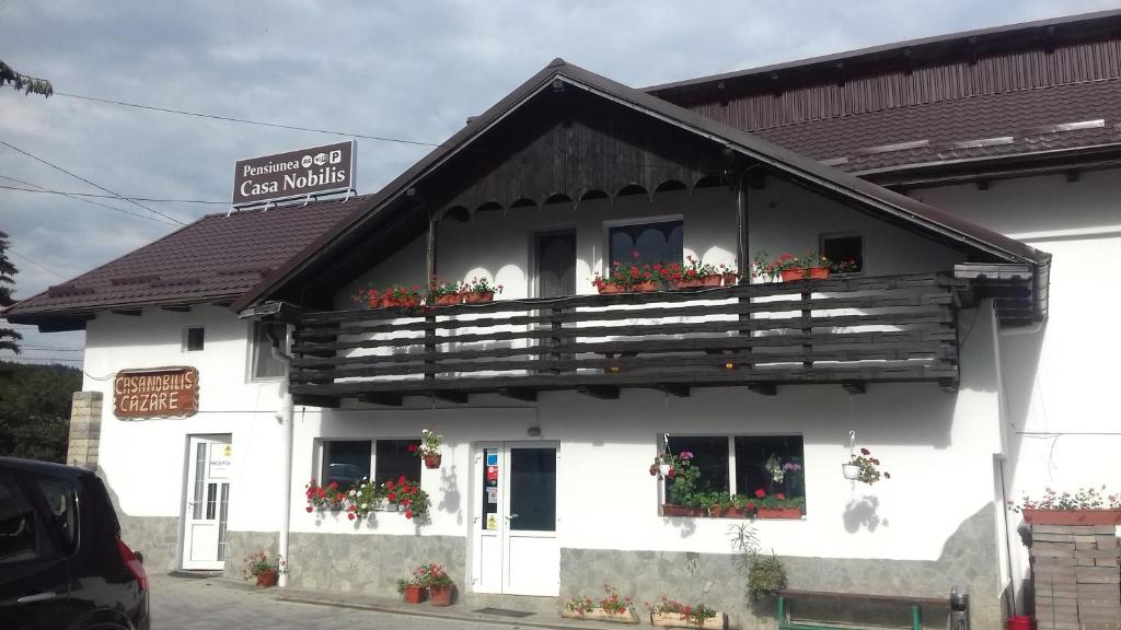 a white building with flower boxes on the balcony at Casa Nobilis in Gura Humorului