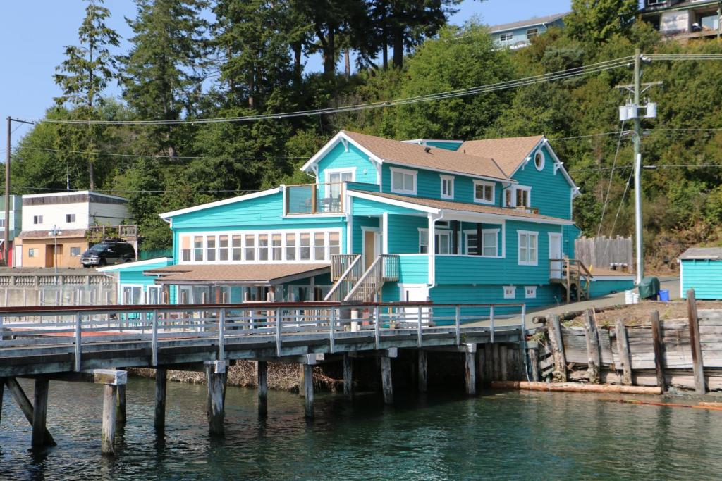 a blue house on a pier next to the water at Nimpkish Hotel in Alert Bay