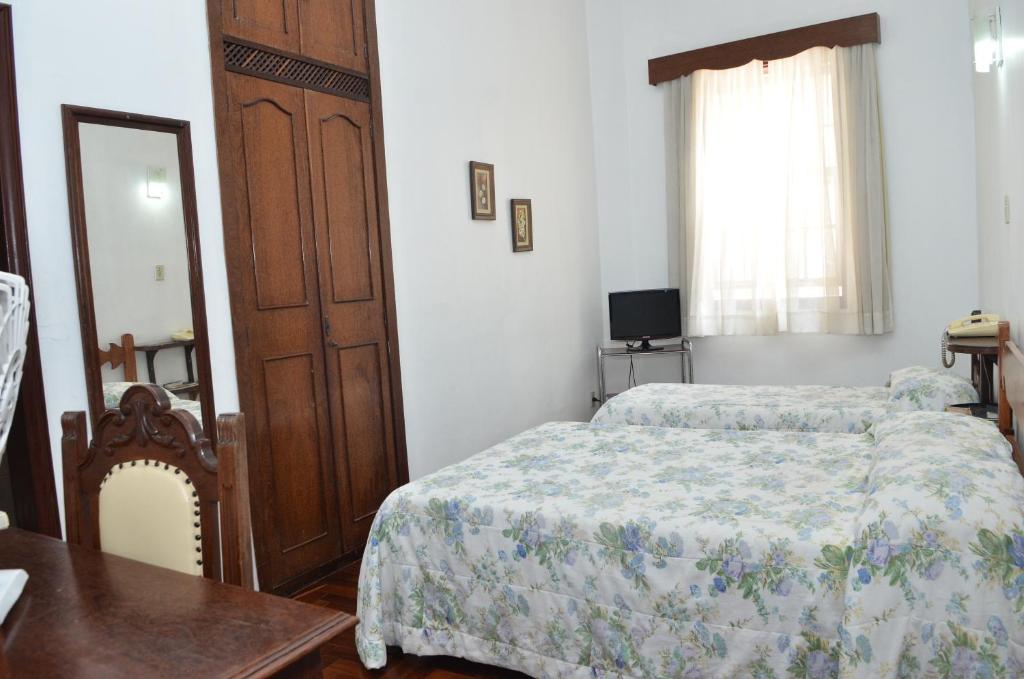 a bedroom with a bed and a table and a mirror at Hotel Priskar in Ouro Preto