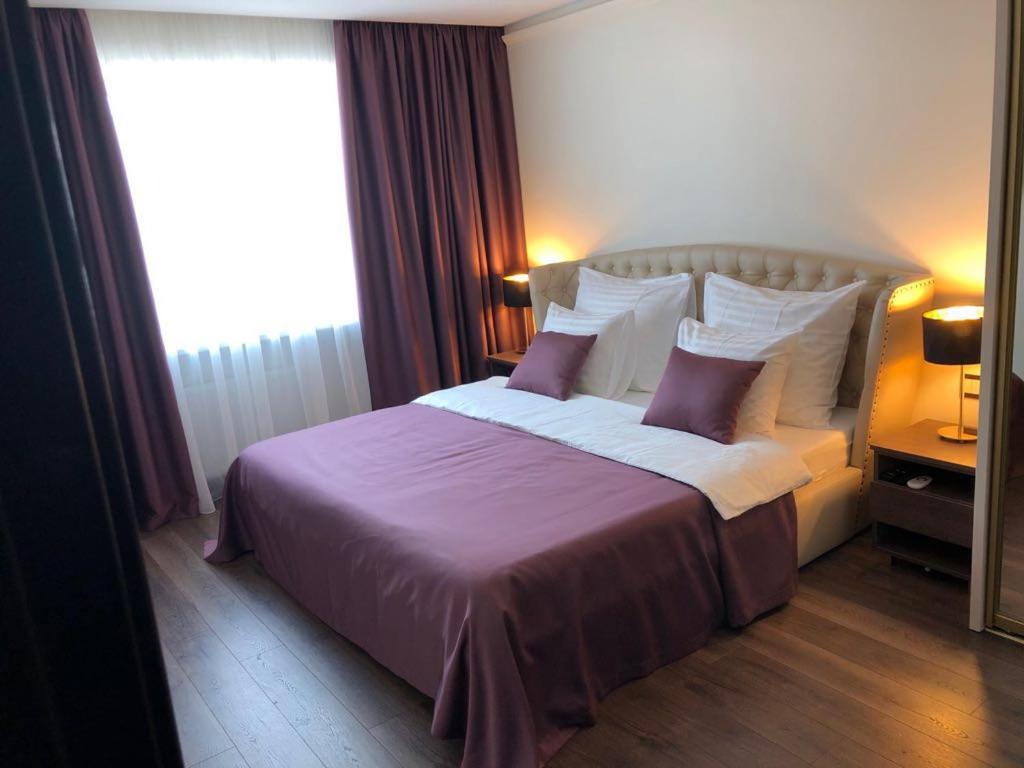 ein Schlafzimmer mit einem großen Bett mit lila Bettwäsche und Kissen in der Unterkunft MARBEO 5 star luxury suites - Elkonu in Liepāja