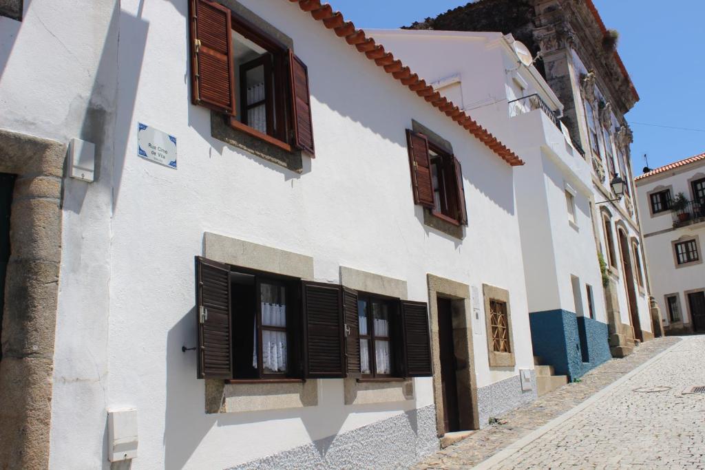 un edificio blanco con persianas marrones en una calle en Casa Cimo Vila en Provesende